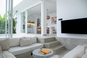 een woonkamer met een bank en een flatscreen-tv bij White Palm Villa in Canggu
