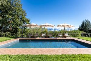 a swimming pool with two umbrellas and two chairs at Chianti Villa Chicco, piscina privata, ampio giardino, BBQ e parcheggio in Greve in Chianti