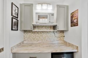 a kitchen with white cabinets and a microwave at DOWNTOWN Hawaiian Theme Condo with Hot Tub, Pool & Beach - Kona Islander Inn in Kailua-Kona
