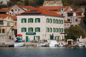 een gebouw met boten in het water naast een stad bij Hotel Maestral in Prvić Luka