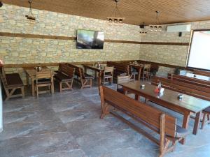a restaurant with wooden tables and chairs and a tv on a brick wall at Комплекс Кантона in Razhishte