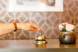 una mujer alcanzando una campana sobre una mesa en Grand Hôtel Du Nord, en Vesoul
