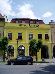 a black car parked in front of a yellow building at Hotel Arkada in Levoča