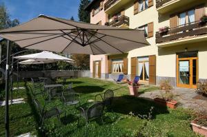 a patio with a table and chairs and an umbrella at Residence Stella Alpina in Aprica