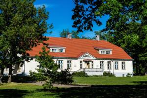 une grande maison blanche avec un toit orange dans l'établissement Loona Manor Guesthouse, à Kihelkonna