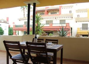 a wooden table and chairs on a balcony with a building at Apartamento Costa de la Luz Golf y Playa in Ayamonte
