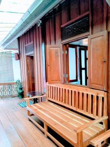 a wooden bench sitting on the porch of a house at Ireenkevin guesthouse in Luang Prabang