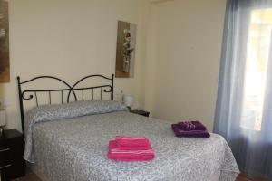 a bedroom with a bed with two pink towels on it at Apartamento Costa de la Luz Golf y Playa in Ayamonte
