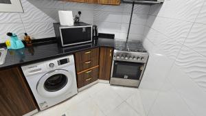 a kitchen with a washing machine and a microwave at Lavish Private Rooms in Sharjah