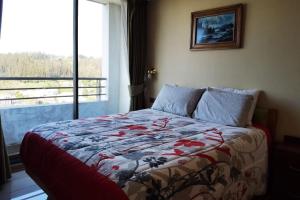 ein Schlafzimmer mit einem Bett mit einer Steppdecke darauf in der Unterkunft Depto con la mejor vista a la ciudad de Concepción in Concepción