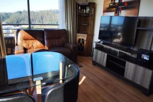 ein Wohnzimmer mit einem TV und einem Glastisch in der Unterkunft Depto con la mejor vista a la ciudad de Concepción in Concepción
