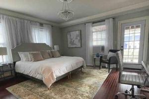 a bedroom with a bed and a chair and windows at C&J Signature Stays Downtown Apartment in Morristown