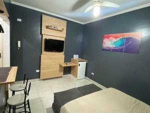 Un dormitorio con una cama, un escritorio y un televisor. en kitnet Premium ao lado da praia Canto do Forte, en Praia Grande