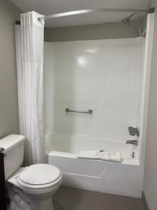 a white bathroom with a toilet and a tub and a shower at Cambridge Inn in Oklahoma City