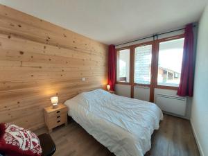 sypialnia z drewnianą ścianą z łóżkiem i 2 lampami w obiekcie Appartement cosy 3 pièces avec 2 balcons, lave-vaisselle, lave-linge, à proximité des pistes - FR-1-353-126 w mieście La Plagne Tarentaise