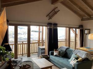 un salon avec un canapé bleu et un balcon dans l'établissement Appartement 3 pièces cosy avec piscine et parking à La Plagne - FR-1-353-123, à La Plagne Tarentaise
