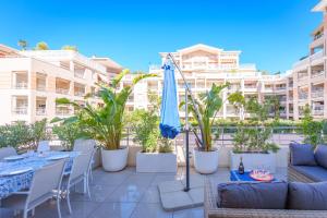 a patio with a table and a blue umbrella at Les VOILES DE GOLFE in Golfe-Juan