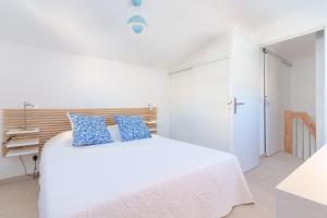 a white bedroom with a white bed with blue pillows at Les VOILES DE GOLFE in Golfe-Juan