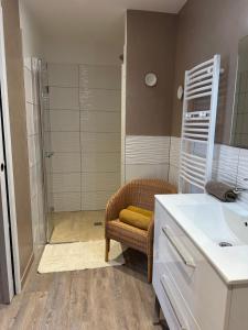 a bathroom with a chair and a sink and a shower at Chambre Tuffeau "Belle An Pierre chambres d hôtes & spa" in Saint-Cyr