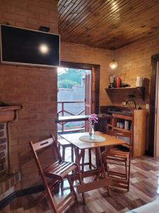 Chalés das cerejeiras في سانتو أنطونيو دو بينهال: غرفة طعام مع طاولة وكراسي وتلفزيون