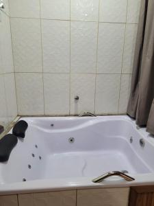 Chalés das cerejeiras في سانتو أنطونيو دو بينهال: حوض استحمام أبيض في حمام مع دش