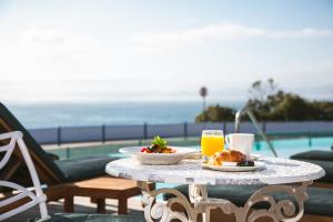 een tafel met een bord eten en twee glazen sinaasappelsap bij Harbour House Hotel - Harbour Square in Hermanus