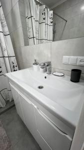 a white bathroom with a sink and a mirror at Grey & White Apart in Vinnytsya