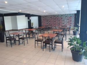 a dining room with tables and chairs and a brick wall at Hotel Safari in Iquitos