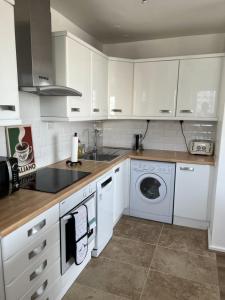 a kitchen with white cabinets and a washing machine at Highrise in Shoreditch in London +24 photos