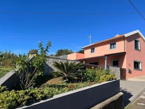 a house with a retaining wall in front of it at The Cozy Pink House in Ponta do Sol