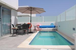 une piscine avec un parasol à côté d'une table et une table dans l'établissement Villa Marina Rubicón DeLuxe, à Playa Blanca