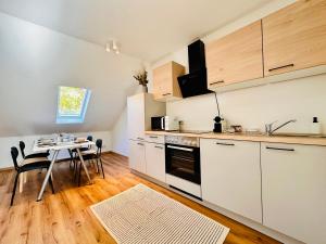 a kitchen with white cabinets and a dining table at Apartment Mirador an der Hohen Wand in NÖ in Grünbach am Schneeberg