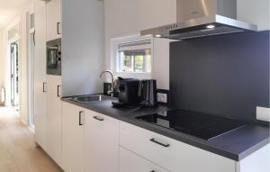 a kitchen with white cabinets and a black counter top at 2 Bedroom Awesome Home In Hellendoorn in Hellendoorn