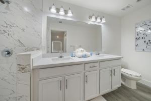 een badkamer met een wastafel, een toilet en een spiegel bij Brand New House! 10 Minutes To The Beach! in West Palm Beach +28 foto's