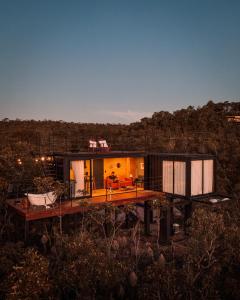 a small house on a wooden deck in a field at Refúgio Veadeiros Container in Sao Jorge