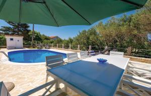 a table with a green umbrella next to a pool at 2 Bedroom Awesome Apartment In Barbat in Barbat na Rabu +26 photos