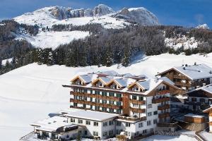 a hotel in the snow with a mountain at Family & Wellness Hotel Fontana in Vigo di Fassa
