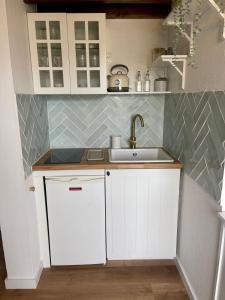 a kitchen with white cabinets and a sink at La Cabane Rennaise in Rennes +5 photos