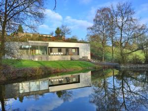 een huis dat reflecteert in het water van een rivier bij Ard'cube in Noiseux