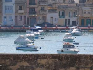Un grupo de barcos en un cuerpo de agua con edificios. en Birzebbugia - 100m from beach & promenade, en Birżebbuġa
