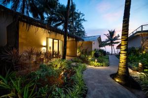 a house with a palm tree next to a walkway at Palma Beach Resort in Mandrem