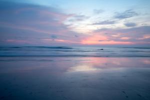 a sunset on a beach with the ocean at Palma Beach Resort in Mandrem