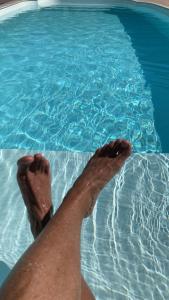 a person with their feet in a swimming pool at Bangalô Pontal do Atalaia com piscina para casal ou família in Arraial do Cabo
