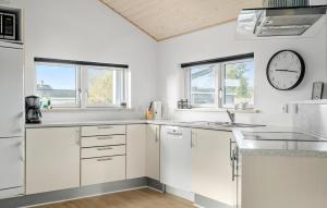 a kitchen with white cabinets and a clock on the wall at Amazing Home In Tarm With Sauna in Tarm +30 photos