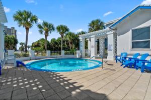 a swimming pool with blue chairs and palm trees at Seas The Day in Navarre