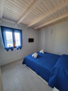 a bedroom with a blue bed and two windows at Appartamenti Vincenzo Lampedusa in Lampedusa