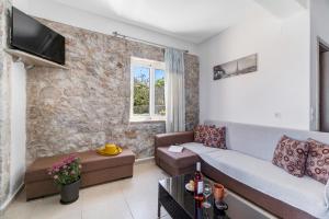 a living room with a couch and a tv on a wall at Gkountis stone apartment 5 in Tsoukaladhes