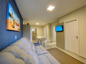 a living room with a couch and a flat screen tv at Ondas do Mar Residencial in Bombinhas