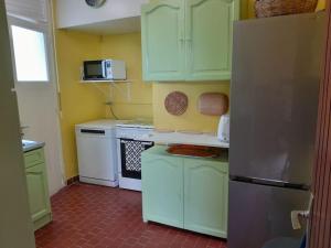 a kitchen with green cabinets and a refrigerator at LaVieLà in Saint-Claude