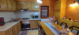 a kitchen with wooden cabinets and a table with flowers on it at Cabana Corbu Băile Figa in Beclean